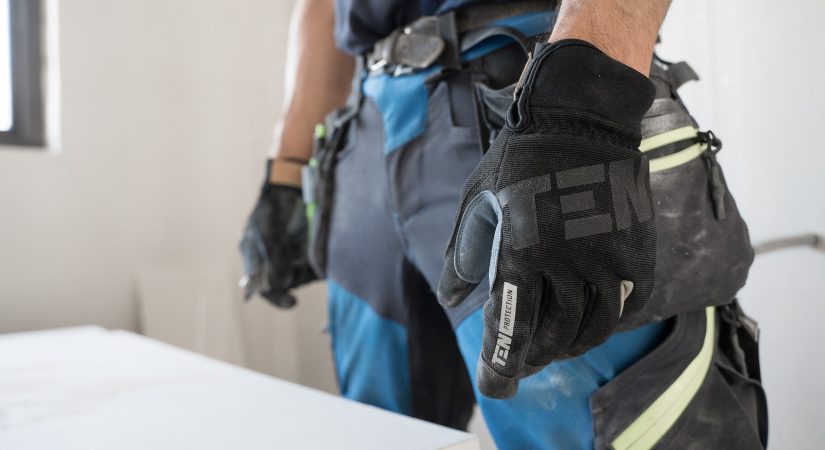 a man wearing a pair of black and blue work gloves